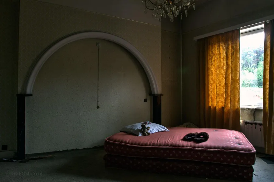 Mattress beneath a large decorative arch in an empty room.