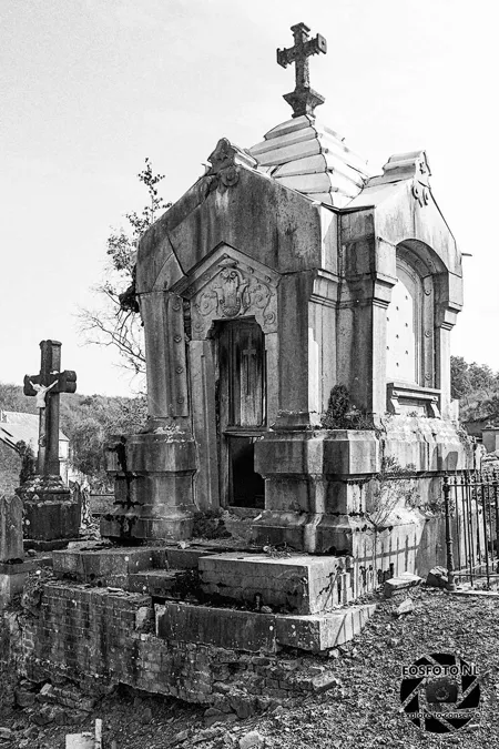Kleine steinerne Grabkapelle mit Kreuz, Stufen und offener Türöffnung.