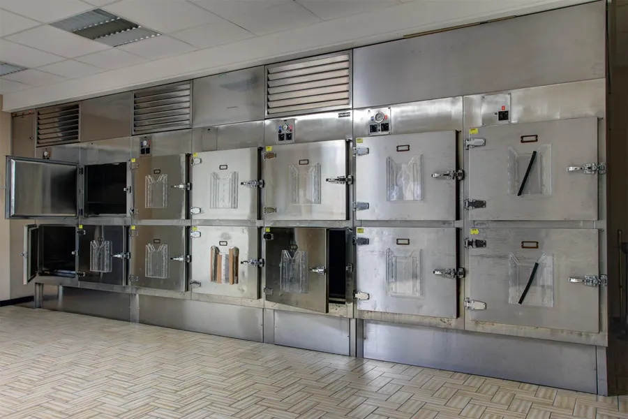 Row of metal refrigeration compartments in the mortuary, some open.