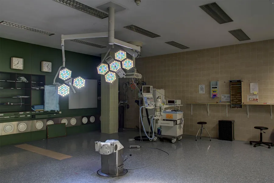 Illuminated surgical lights above an empty table pedestal and remaining equipment.