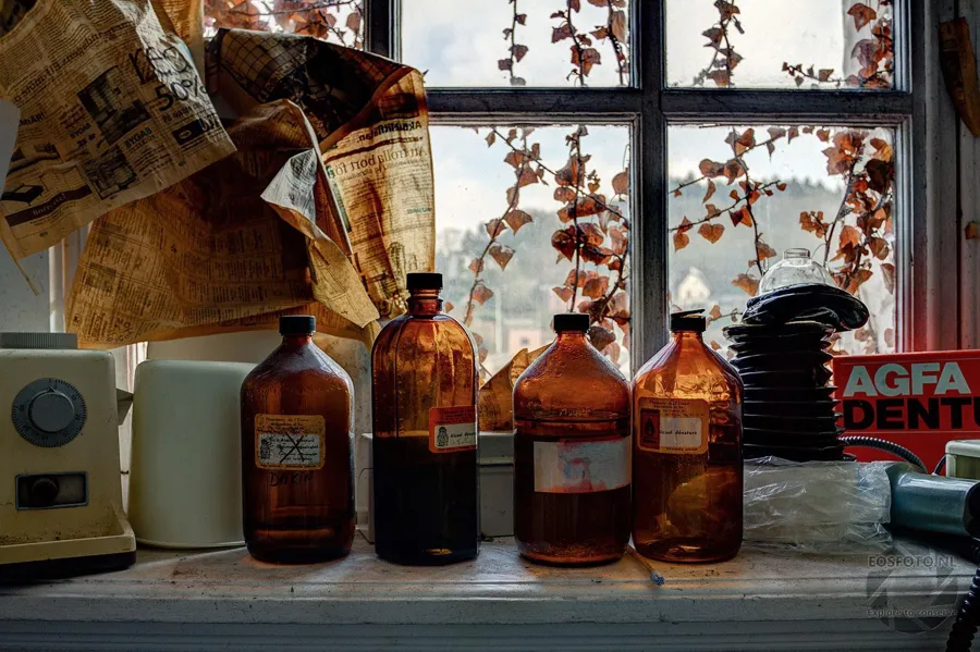 Brown glass bottles on a windowsill with old paper and leaves.