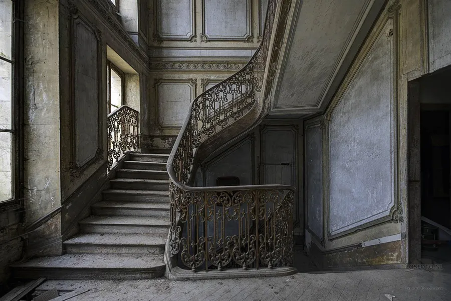 Curving stone staircase with decorative metal balustrade