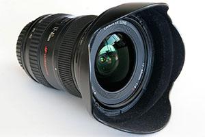 Canon-17–40mm-Objektiv mit rotem Ring und tulpenförmiger Gegenlichtblende, schräg von vorn.