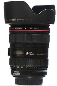 Schwarzes Canon-24–105mm-Objektiv mit rotem Ring und breiter Gegenlichtblende, aufrecht abgebildet.