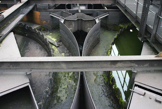Concrete water channels with green water beneath metal gratings