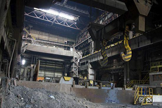 Yellow crane hooks above a pile of material in the large production hall