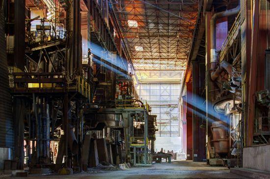 Beam of light through a tall production hall with several levels and pipes