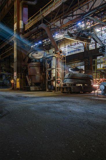 Wide factory space with tall installations and a sunbeam near the roof