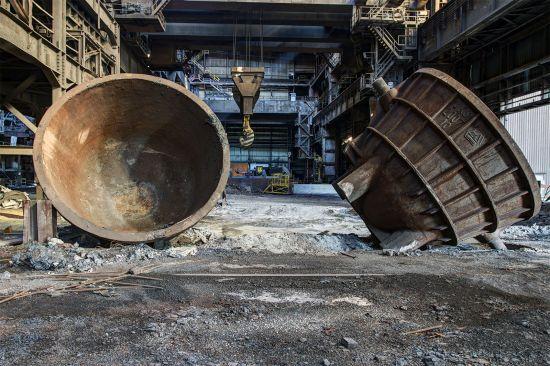 Two large tilted casting vessels on the floor of a factory hall