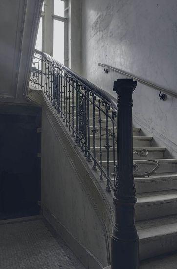 Escalera de piedra con barandilla metálica ornamentada bajo una ventana